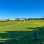 Alcino Soutinho's Soutinho 14 Villas at Bom Sucesso Resort in Obidos showcasing modern architecture with a natural environment, featuring green grassland and a clear blue sky.