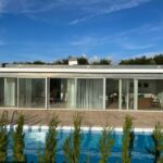 Alcino Soutinho's design of the Soutinho 14 Villas at Bom Sucesso Resort in Obidos, showcasing a modern concrete structure with composite materials, a swimming pool, and outdoor shading elements.