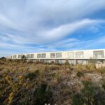 Alcino Soutinho's design of the Soutinho Conjunto de 28 Habitações em Banda at Bom Sucesso Resort, Obidos, showcasing a modern villa with concrete structures, extensive landscaping, and daylighting features surrounded by a garden and shrubs.
