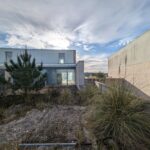 Alcino Soutinho's design of the Soutinho Conjunto de 28 Habitações em Banda at Bom Sucesso Resort, Obidos, showcasing a modern residential complex with a grass-covered landscape and herbaceous plants.