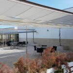 Álvaro Siza Vieira's O Espaço de Siza no Bom Sucesso – Nave Lagoa at Bom Sucesso Resort, Obidos, showcasing a minimalist design with a plain landscape surrounded by grass, shrubs, and rural groundcover.