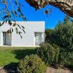 Álvaro Siza Vieira's Siza 14 Villas no Bom Sucesso at the Bom Sucesso Resort in Obidos, showcasing a modern architectural design with a landscaped garden featuring grass, shrubs, and a plant community.