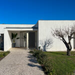 Álvaro Siza Vieira's Siza 14 Villas no Bom Sucesso showcasing a modern concrete structure with a landscaped garden, driveway, and surrounding shrubs at the Bom Sucesso Resort in Obidos.