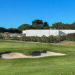 Álvaro Siza Vieira's O Espaço de Siza no Bom Sucesso – Nave Lagoa at Bom Sucesso Resort, Obidos, showcasing a modern sports venue surrounded by well-maintained grassland and landscaping.