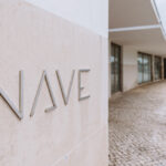 Álvaro Siza Vieira's design of the Bom Sucesso Resort in Obidos, featuring a modern outdoor structure with a steel pergola providing shade over a courtyard with outdoor furniture and a restaurant area.