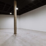 Álvaro Siza Vieira's O Espaço de Siza no Bom Sucesso – Nave Lagoa at Bom Sucesso Resort, Obidos, showcasing an interior design with composite material flooring, a transparent ceiling, and an exhibition hall.