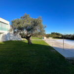 David Chipperfield's Chipperfield 4 Villas no Bom Sucesso at the Bom Sucesso Resort in Obidos, showcasing a modern design with a landscaped garden, expansive lawn, and a swimming pool casting shadows.