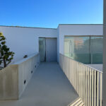 David Chipperfield's Chipperfield 4 Villas at Bom Sucesso Resort in Obidos showcasing a modern design with grey concrete and plaster materials, featuring balconies with handrails and ample daylighting.