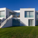 David Chipperfield's Chipperfield 4 Villas no Bom Sucesso at the Bom Sucesso Resort in Obidos, showcasing a modern residential design with a landscaped garden, expansive lawn, and villa-style architecture.